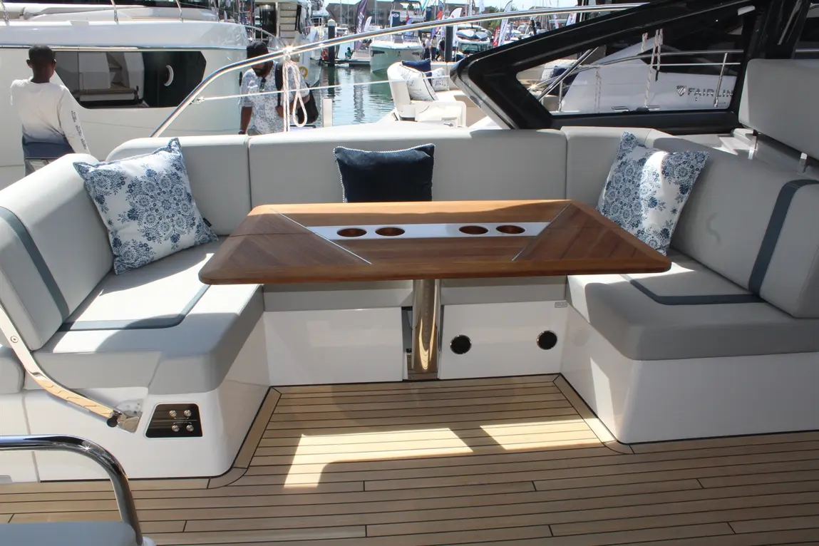 Modern boat interior featuring a stylish seating area, a wooden table with cup holders, and blue patterned cushions.